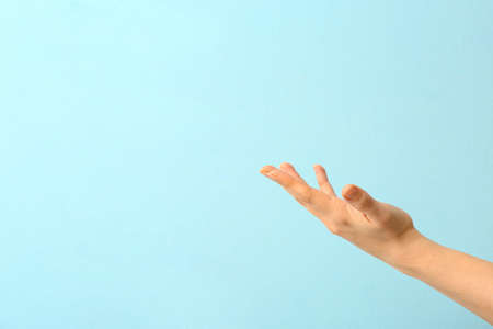 Hand of woman suffering from Parkinson syndrome on color background