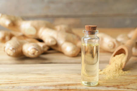 Bottle with ginger essential oil on wooden tableの写真素材