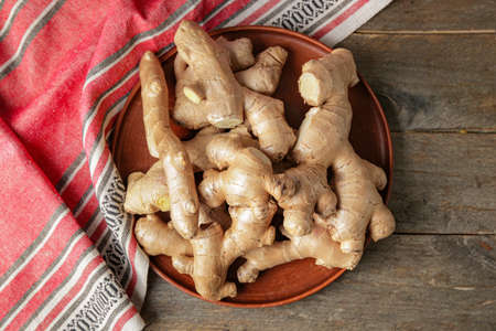 Plate with fresh ginger on wooden tableの写真素材
