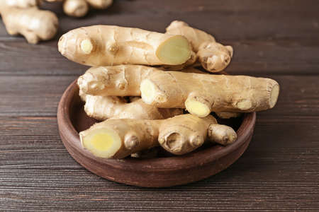 Plate with fresh ginger on wooden tableの写真素材