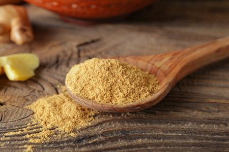 Spoon with ground ginger on wooden tableの写真素材
