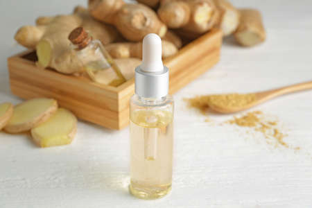 Bottle with ginger essential oil on white tableの写真素材