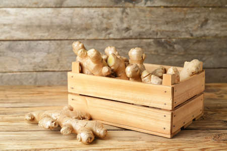 Box with fresh ginger on wooden tableの写真素材
