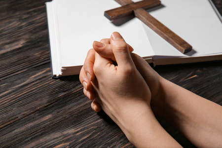 Hands of praying woman, Bible and cross on wooden backgroundの写真素材
