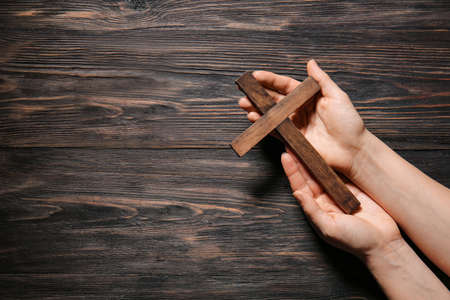 Female hands with christian cross on wooden backgroundの写真素材