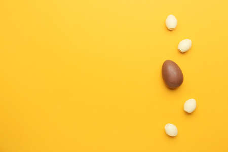 Brown chocolate Easter egg among white ones on color background. Concept of uniquenessの写真素材