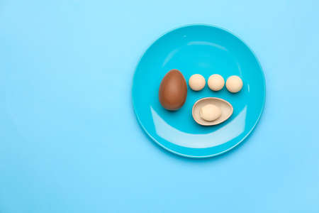 Plate with chocolate Easter eggs on color backgroundの写真素材