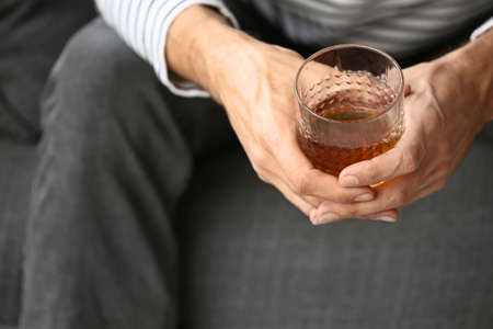 Depressed young man drinking alcohol at home, closeupの写真素材