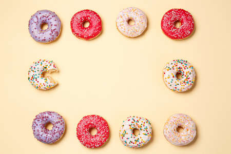 Frame made of sweet tasty donuts on color backgroundの写真素材