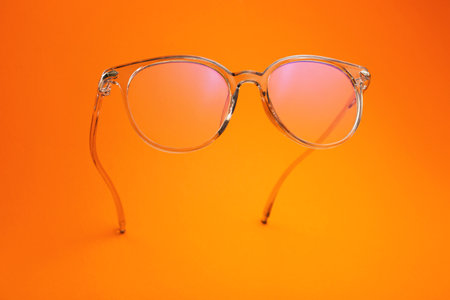 Stylish eyeglasses on color background