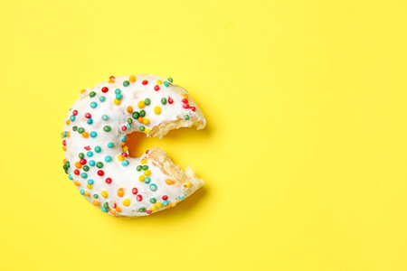 Sweet bitten donut on color backgroundの写真素材