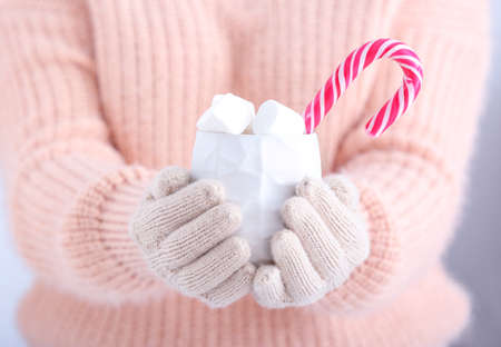 Woman with knitted gloves and cup of hot chocolate, closeup