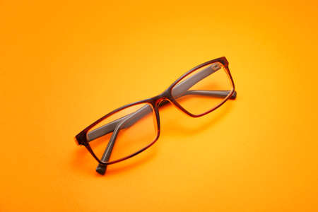 Stylish eyeglasses on color background