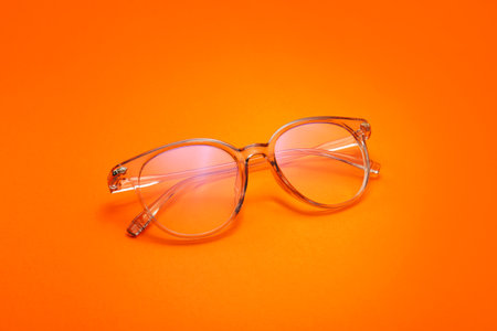 Stylish eyeglasses on color background
