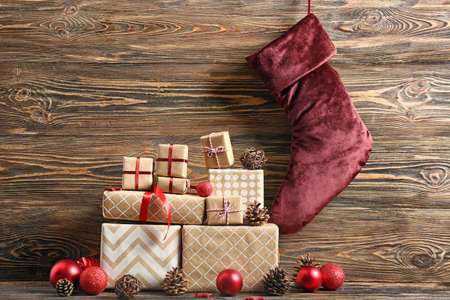 Christmas sock with gifts on wooden background