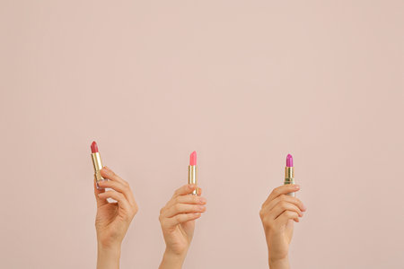 Female hands with lipsticks on color backgroundの写真素材