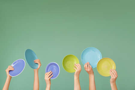 Hands with different clean plates on color backgroundの写真素材