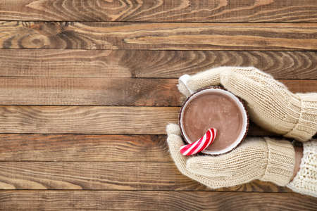 Female hands with cup of hot chocolate on wooden backgroundの写真素材
