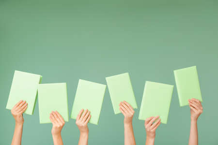 Female hands with books on color backgroundの写真素材