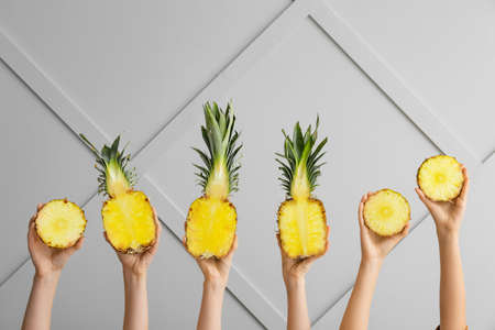 Hands with juicy pineapples on light backgroundの写真素材