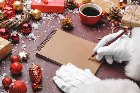 Santa Claus writing something in notebook on tableの写真素材