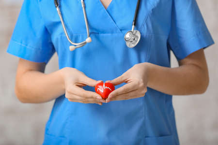 Female cardiologist with red heart on light backgroundの写真素材