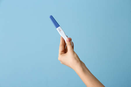 Female hand with pregnancy test on color backgroundの写真素材