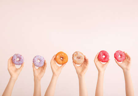 Female hands with sweet donuts on color backgroundの写真素材