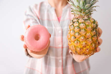 Woman with sweet donut and pineapple on light backgroundの写真素材