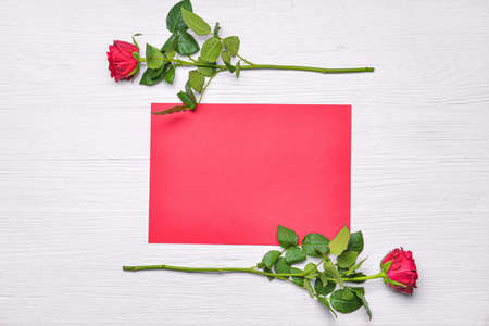 Beautiful rose flowers with empty paper sheet on white background. International Women's Day...