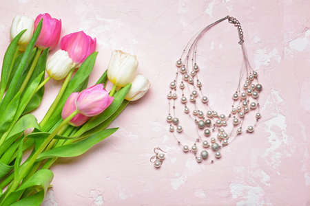 Beautiful tulip flowers with jewelry on color background. International Women's Day celebrationの写真素材