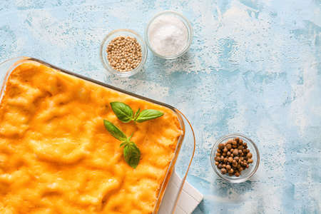 Baking dish with prepared lasagna on color background