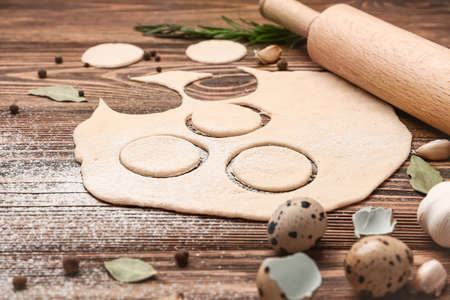 Composition with dough for dumplings on wooden background