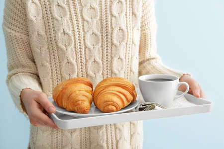 Woman holding tray with tasty croissants and coffee, closeup