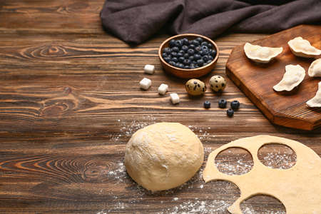 Raw dough and dumplings with ingredients on wooden backgroundの写真素材