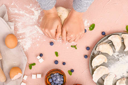 Woman cooking tasty dumplings on color background