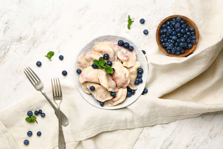 Plate with tasty dumplings and blueberry on tableの写真素材