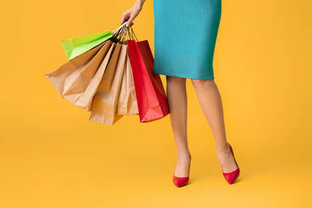 Beautiful young woman with shopping bags on color background