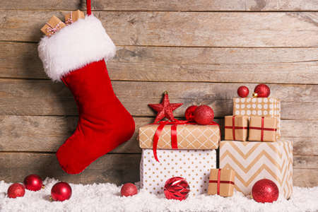 Christmas sock with gifts on wooden background