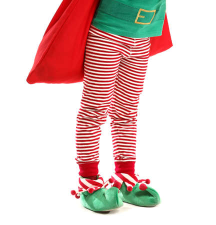 Little girl in costume of elf and with Santa Claus bag on white backgroundの写真素材