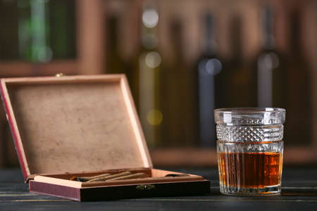 Glass of whiskey with cigars on table in barの写真素材