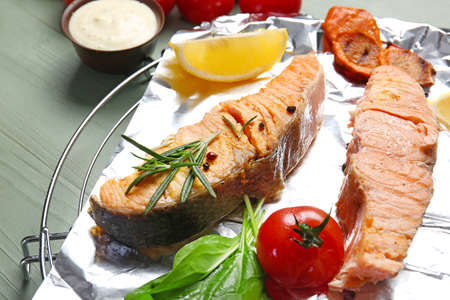 Cooling rack with tasty cooked salmon and vegetables on table, closeupの写真素材