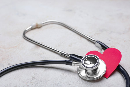 Stethoscope and heart on light background. Cardiology concept