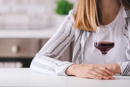 Woman with glass of wine at home. Concept of alcoholismの写真素材