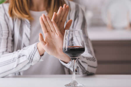 Woman refusing to drink wine at home. Concept of alcoholismの写真素材