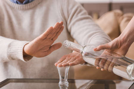 Man refusing to drink vodka at home. Concept of alcoholismの写真素材