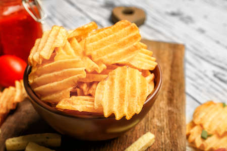 Bowl with tasty potato chips on table
