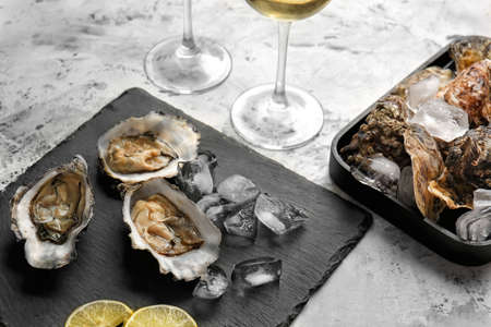 Slate plate with tasty cold oysters and wine on white backgroundの写真素材