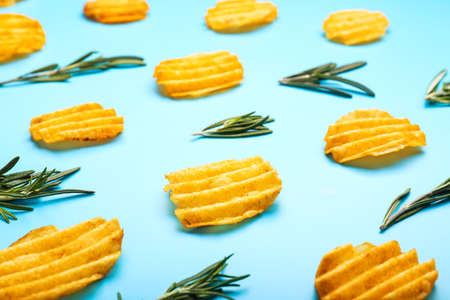 Tasty potato chips and herbs on color background