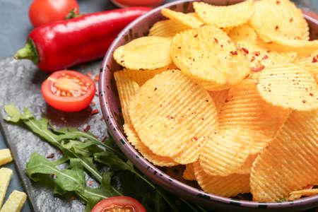 Plate with tasty potato chips on table, closeup